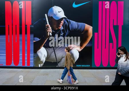 London, Großbritannien. 23. September 2025. Die Menschen geben ein Bild von Golfspieler Rory McIlroy auf dem Bauwerk des Außenbereichs des Nike Stores, der gerade renoviert wird, im Oxford Circus. Rory McIlroy ist eines der wichtigsten Mitglieder des Teams Europa, das vom 23. Bis 28. September im Ryder Cup in Bethpage Black in New York gegen die Vereinigten Staaten antritt und unter der Führung von Kapitän Luke Donald den ersten Auswärtssieg beim Ryder Cup seit dem „Miracle at Medinah“ von 2012 erringen kann. Viele europäische Unterstützer hoffen, dass sie es einfach tun. Quelle: Stephen Chung / Alamy Live News Stockfoto