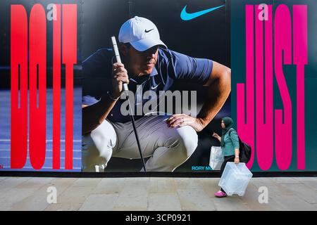 London, Großbritannien. 23. September 2025. Die Menschen geben ein Bild von Golfspieler Rory McIlroy auf dem Bauwerk des Außenbereichs des Nike Stores, der gerade renoviert wird, im Oxford Circus. Rory McIlroy ist eines der wichtigsten Mitglieder des Teams Europa, das vom 23. Bis 28. September im Ryder Cup in Bethpage Black in New York gegen die Vereinigten Staaten antritt und unter der Führung von Kapitän Luke Donald den ersten Auswärtssieg beim Ryder Cup seit dem „Miracle at Medinah“ von 2012 erringen kann. Viele europäische Unterstützer hoffen, dass sie es einfach tun. Quelle: Stephen Chung / Alamy Live News Stockfoto