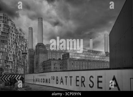 Schwarzweiß-Foto des Kraftwerks Battersea in London, Großbritannien, mit seinen berühmten Schornsteinen und dramatischen Wolken, von einem öffentlichen Fußweg aus gesehen Stockfoto