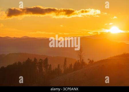 Die Golden Hour beleuchtet die Berge mit einem Himmel in warmen Farben während eines atemberaubenden Sonnenaufgangs. Stockfoto