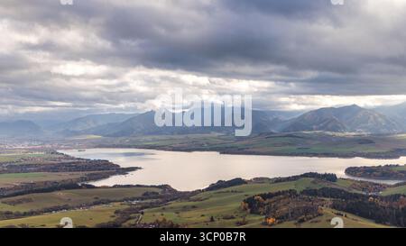 Der Staudamm Liptovska Mara in der nördlichen Slowakei, Europa. Dramatische Berglandschaft mit einem ruhigen See und weitläufigem bewölktem Himmel. Sanfte Hügel hinein Stockfoto