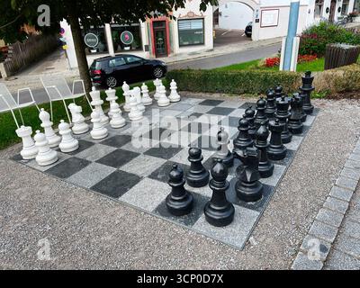 Neubeuern, Deutschland - 25. September 2022: Buntes Outdoor-Schachbrett mit übergroßen schwarz-weißen Stücken auf einer Straße in Deutschland, einladendes Spiel und c Stockfoto