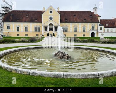 Oberschleissheim, Deutschland - 25. September 2022: Ein großes gelbes Schlosshaus Schleissheim mit rundem Brunnen in einem gepflegten deutschen Garten. Stockfoto