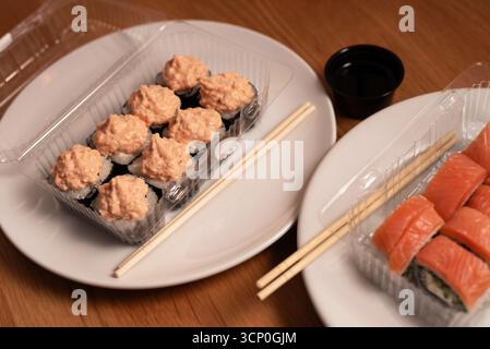 Auf der knusprigen weißen Platte gibt es eine Auswahl an Sushi: Lachsnigiri und Brötchen mit einer cremigen Thunfisch- oder Krabbenmischung. Ideal für Restaurantmenüs Stockfoto