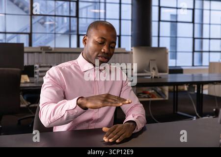 afroamerikaner in Geschäftskleidung sitzt am Schreibtisch im Büro und präsentiert Stockfoto