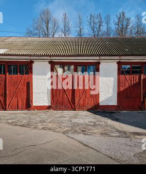 Versorgungsgebäude mit drei Garagentüren - Scheune oder Schuppen. Garagenblock mit bräunlich-roten Holztüren. Stockfoto