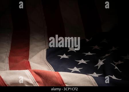 Nahaufnahme des Stoffes mit amerikanischer Flagge mit sichtbaren Falten und Nähten für eine klare patriotische Hintergrundstruktur. Stockfoto