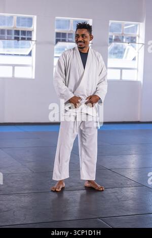 afroamerikaner mit weißem Gi und schwarzem Hemd, barfuß auf Matten im Dojo Stockfoto