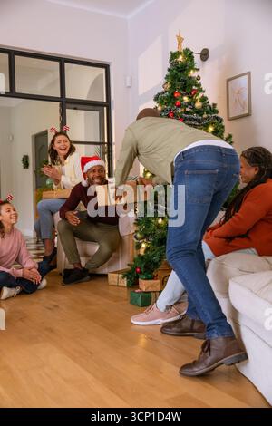 Vielfältige Familiengeschenke beim weihnachtsbaum im Wohnzimmer in Geweih-Stirnbändern Stockfoto