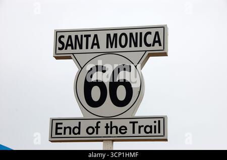 Das legendäre „End of the Trail“-Schild der Route 66 in Santa Monica, Kalifornien, markiert den westlichen Endpunkt des historischen Highway unter einem bewölkten Himmel Stockfoto