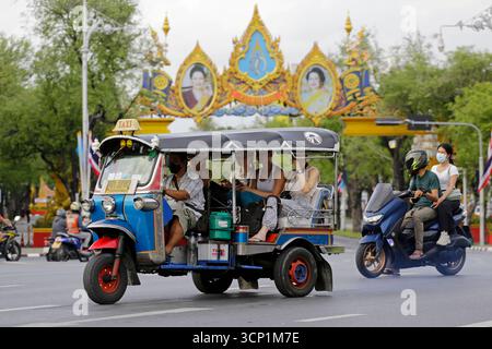 Bangkok, Thailand - 6. August 2022: Thai Tuk Tuk-Fahrer transportieren Touristen durch eine große Straße in der Nähe der Khaosan Road. Stockfoto