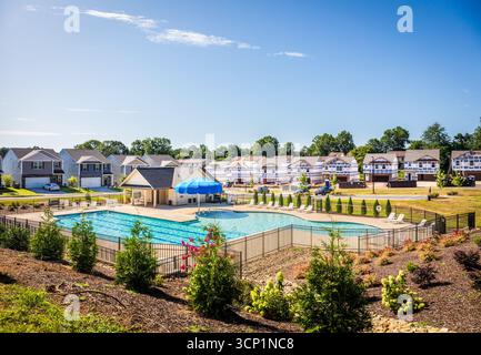Hickory, North Carolina, USA-14. Juli 2025: Badehaus in neuer Wohnsiedlung mit Haus im Bau in der Ferne. Stockfoto