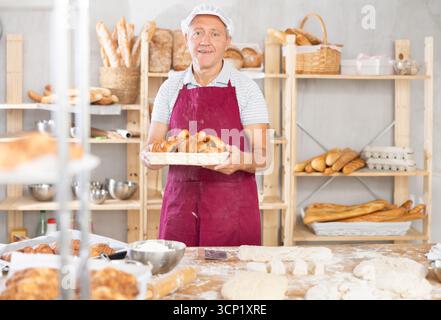 Erfolgreich gereifter Bäcker, der Croissants in der Bäckerei hält Stockfoto