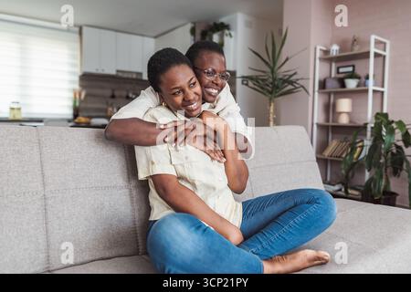 Mutter und Tochter umarmen sich auf dem Sofa und genießen eine schöne Zeit zusammen Stockfoto