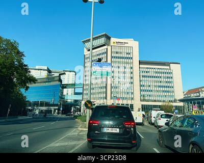 Wien, Österreich - 22. Oktober 2024: Eine pulsierende urbane Szene mit modernen Türmen, Richtungsschildern und Verkehr in Wien, Österreich. Stockfoto