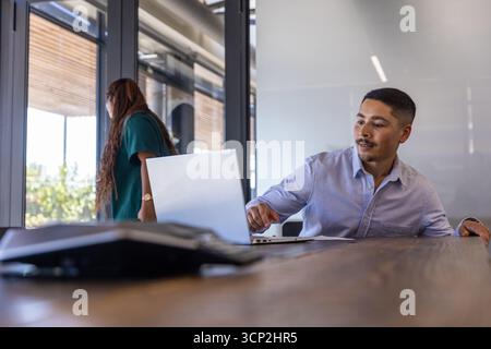 Verschiedene Kollegen diskutieren Ideen auf einem Laptop im Besprechungsraum mit Smartphone und Kopierraum Stockfoto