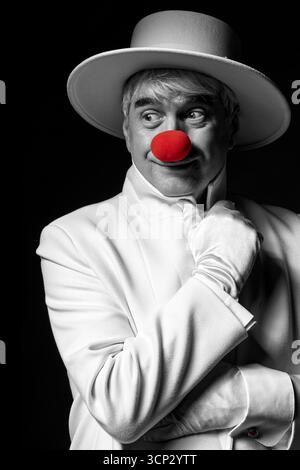 Nahaufnahme selektives Farbporträt eines Clown. Ein älterer Mann mit weißem Mantel und Hut. Stockfoto