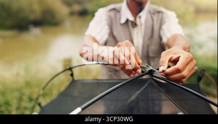 Hände, Mann und Stellzelt für Camping-Abenteuer, Reisevorbereitung und Urlaub in der Wildnis. Person, Kabelbinder und Ausrüstung für die Montage Stockfoto