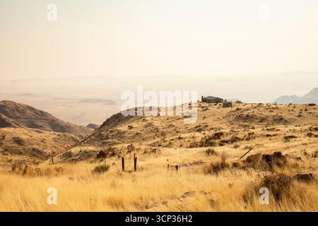 Ein Picknick-Ort überblickt die weite Namib-Wüste vom Spreetshoogte Pass aus mit trüben Ebenen, zerklüfteten Bergen und einem einsamen Haus auf dem Kamm unter dem bri Stockfoto