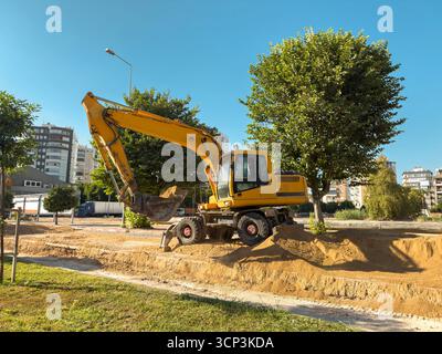 Gelber Bagger, der auf einer Sandbaustelle unter blauem Himmel arbeitet Stockfoto