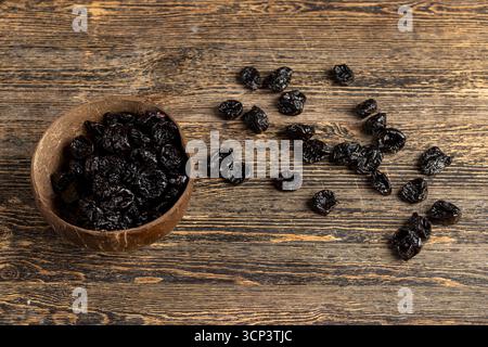 Pflaumen aus Reifen blauen Pflaumen in einer Kokosnussschale, getrocknete Pflaumen in einer Schüssel aus natürlichen Materialien Stockfoto