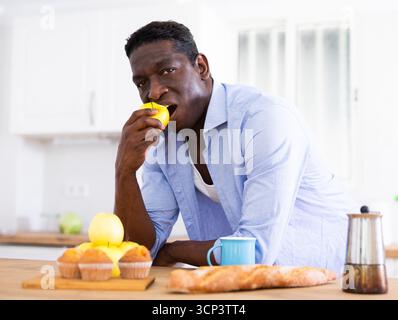 Der Mann isst Äpfel in der Küche während des Frühstücks Stockfoto