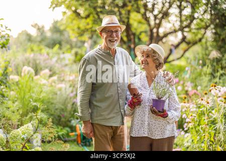 Porträt eines glücklichen Seniorenpaares, das an einem sonnigen Tag im Garten steht Stockfoto