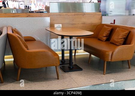 Gemütliches, modernes Café mit braunen Ledersofas, Holztisch und stilvollem Design. Ideales Konzept für Restaurant-, Lounge- oder Coffee Shop-Atmosphäre Stockfoto