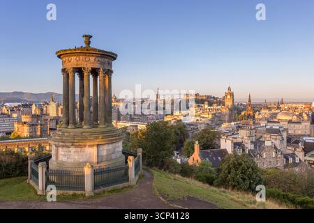 Blick auf das berühmte Dugald Stewart Monument erhebt sich majestätisch auf Calton Hill, mit Blick auf die weitläufige Stadtlandschaft, die sich im warmen Glanz der untergehenden Sonne in Edinburgh, Schottland, sonnt. Stockfoto