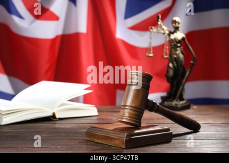 Richterlicher Hammer, Buch und Statue von Lady Justice auf Holztisch vor der Flagge Großbritanniens, Nahaufnahme Stockfoto