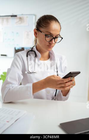 Therapeutin mit Smartphone in der Klinik, SMS-SMS-Beratung der Patientin online. Stockfoto