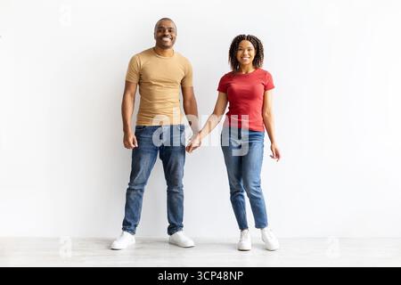 Lächelndes afroamerikanisches Paar, das die Hände aneinander hält, während es der Kamera zugewandt ist Stockfoto