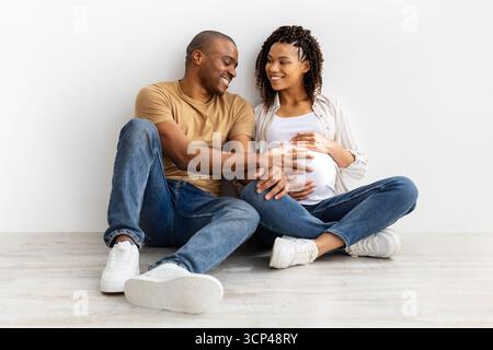 Glückliches schwarzes Paar, das ein Baby erwartet, Mann, der schwangere Frauen mit Liebe berührt Stockfoto