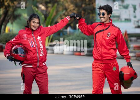 Ein Mann und eine Frau in Red Sports Gear feiern auf einer Go-Kart-Strecke Stockfoto