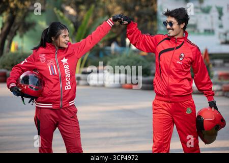 Ein Mann und eine Frau in Red Sports Gear feiern auf einer Go-Kart-Strecke Stockfoto