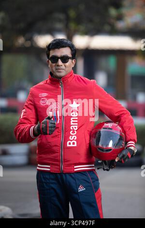 Ein lächelnder Mann gibt ein Siegeszeichen und posiert mit einem roten Motorradhelm Stockfoto