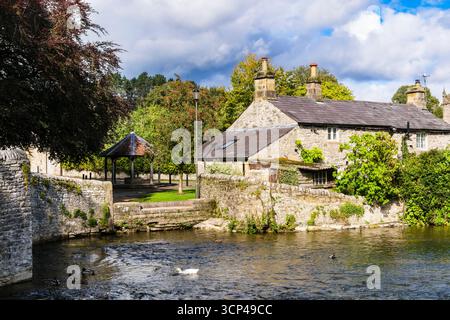 Blick auf die Sheepwash Bridge über den Fluss Wye zum Cottage und Marktstand im Dorf Peak District. Ashford im Wasser, Bakewell, Derbyshire, England Stockfoto