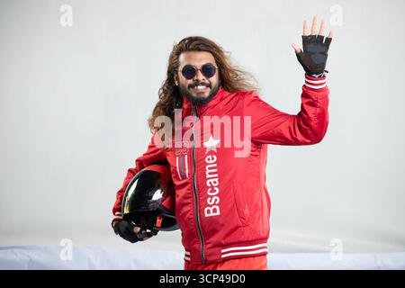 Lächelnder Mann mit langen Haaren und Sonnenbrille, der der Kamera zuwinkt Stockfoto