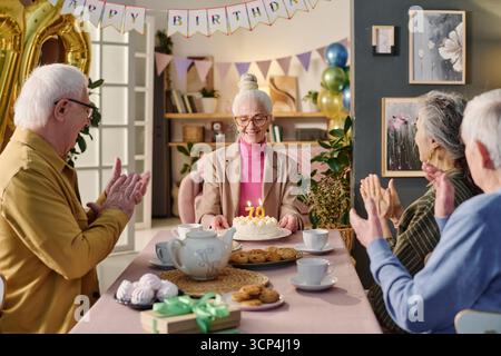 Seniorin feiert Geburtstag mit Freunden am Festtisch Stockfoto