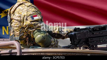 North Carolina US-Staatsflagge mit Soldaten am Maschinengewehr davor. Stockfoto