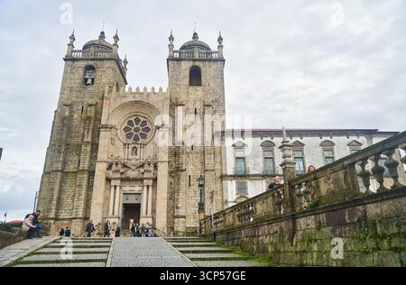 Porto, Portugal - 12.25.2022: Eine historische Kathedrale mit einer atemberaubenden Fassade und großen Steintreppen zum Eingang Stockfoto
