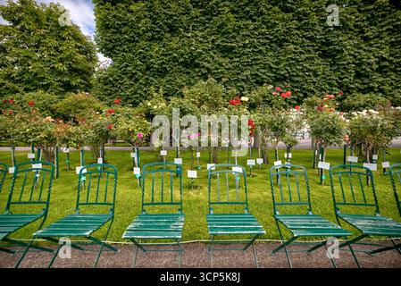 Leere Reihen grüner Stühle säumen die schattigen Wege des Volksgartens in Wien, einem beliebten öffentlichen Garten, der für seine Rosensammlungen und Neo bekannt ist Stockfoto