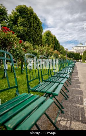 Leere Reihen grüner Stühle säumen die schattigen Wege des Volksgartens in Wien, einem beliebten öffentlichen Garten, der für seine Rosensammlungen und Neo bekannt ist Stockfoto