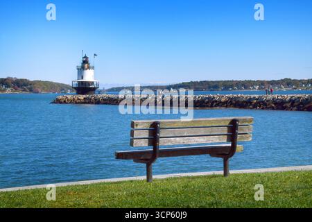 Rustikale Parkbank aus Holz bietet Blick auf den Spring Point Ledge Lighthouse in Portland Harbor, Maine. Stockfoto