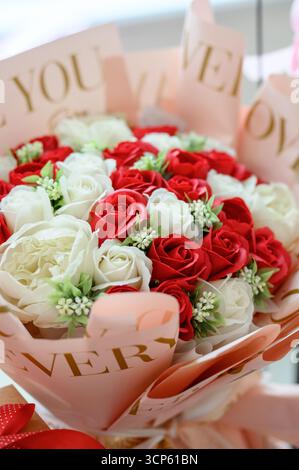 Strauß aus Seifenblumen, die Rosen imitieren, in einer Geschenkbox. Nahaufnahme: Eine Komposition aus künstlichen roten und weißen Rosen in einem eleganten Paket Stockfoto