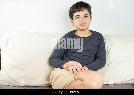12-jähriger brasilianischer Teenager auf der Couch, der ernsthaft in die Kamera schaut. Stockfoto
