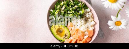 Eine nahrhafte Frühstücksschale mit Reis, Lachs, Avocado und frischem Gemüse wird in einer Schüssel wunderbar präsentiert. Einfache und gesunde Idee für das morgendliche Essen Stockfoto