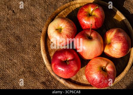 Nahaufnahme mehrerer Äpfel in einer Holzschale auf einem Sackleinen Hintergrund. Konzept von landwirtschaftlichen Erzeugnissen und gesunder Ernährung. Stockfoto
