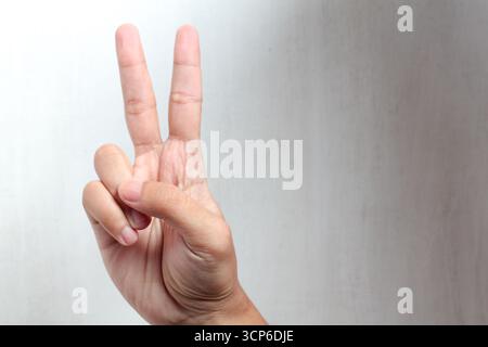 Die menschliche Hand zeigt die Friedensgeste mit zwei Fingern nach oben Stockfoto