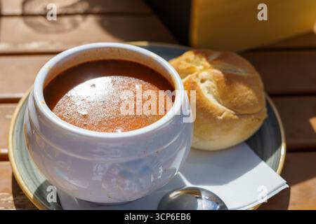 Traditionelle ungarische dicke Gulasch-Suppe auf einem weißen tiefen Teller serviert mit weißem Brot in einem österreichischen Bergcafé Stockfoto